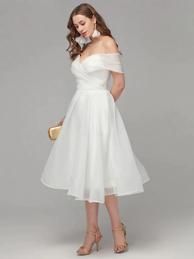 Back view of the elegant white off-shoulder A-line dress, highlighting its flowing tea-length skirt.