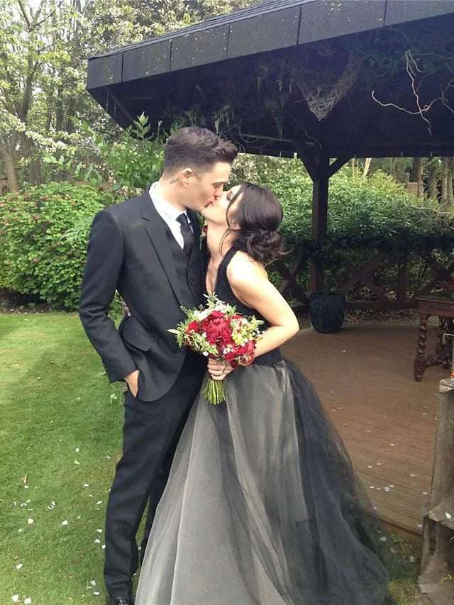 Back view of a modern black halter neck bridal gown, showcasing appliques and flowing satin tulle fabric.