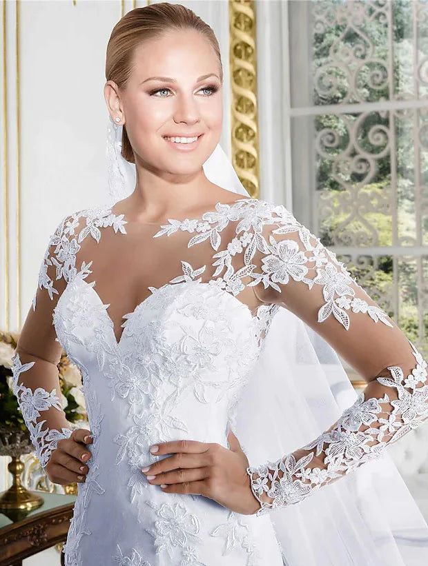 Full view of a bride wearing a white lace long-sleeve wedding dress with a graceful court train.