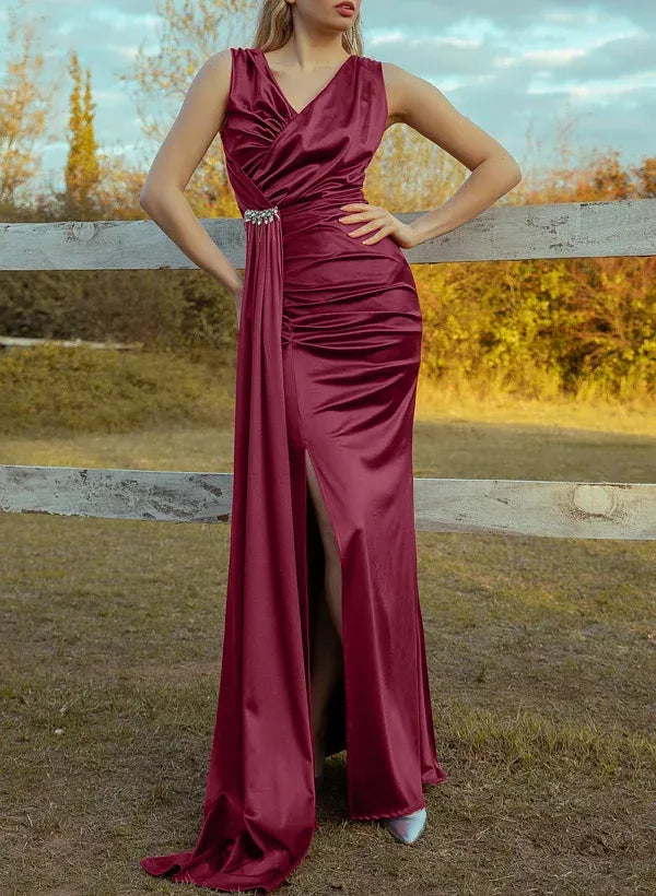 Model wearing a burgundy mermaid prom dress with V-neck, high slit, and crystal-embellished waist.