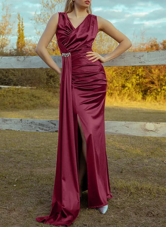 Model wearing a burgundy mermaid prom dress with V-neck, high slit, and crystal-embellished waist.