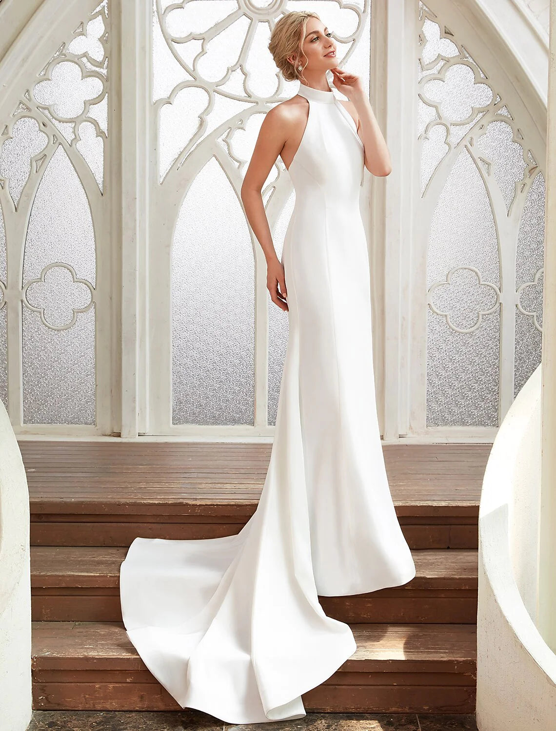 Woman in white halter open back sheath bridal shower dress, front view.