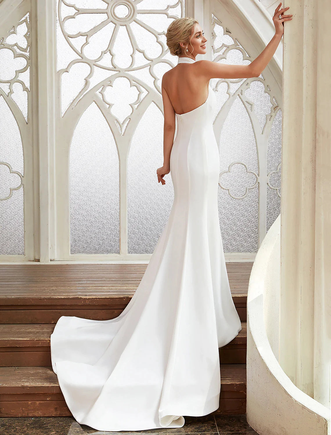 Woman in white halter open back sheath dress, side view, showing open back.