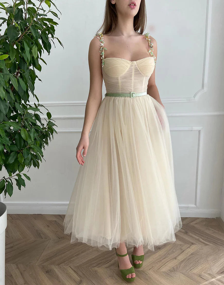 Front view of an apricot A-line tulle homecoming dress with intricate beading on the bodice.