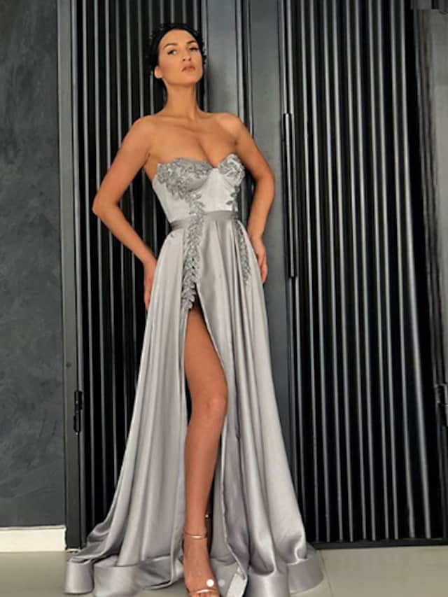 Woman wearing an elegant dark A-line off-shoulder satin prom dress with a high slit.