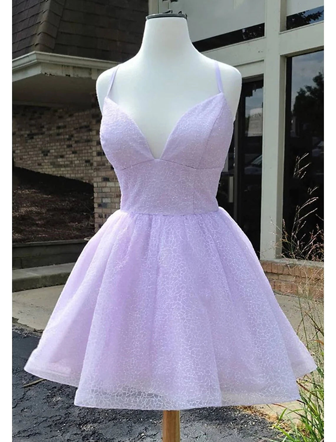 Woman wearing a sparkling A-Line short homecoming dress with spaghetti straps.