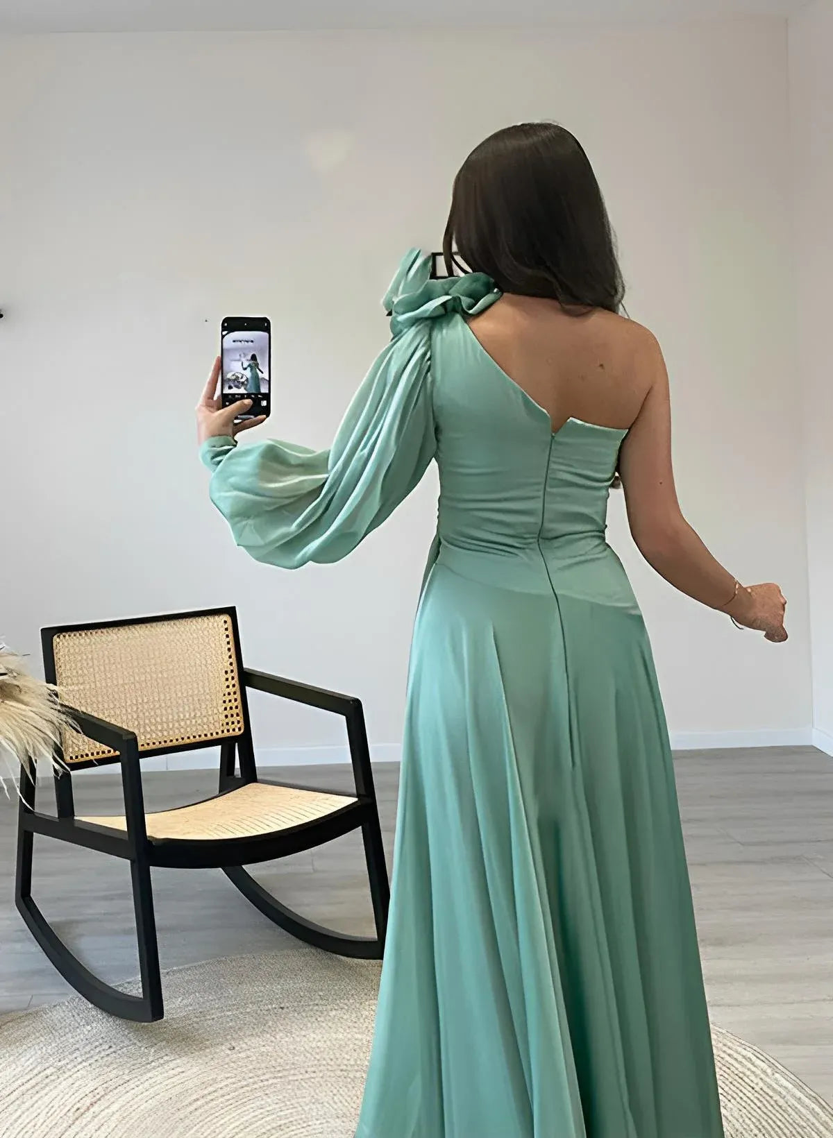 Back view of a model in a dusty teal A-line prom dress, showcasing the floor-length skirt.