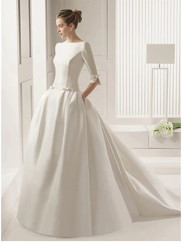 Full view of an elegant white A-line wedding dress with a bateau neck, half sleeves, and court train.