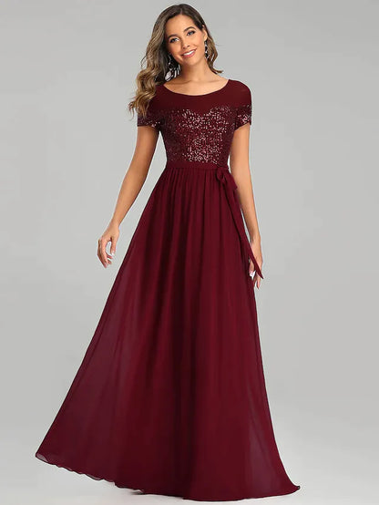 Model in a light blue A-line chiffon bridesmaid dress with a jewel neck and sequin sash.