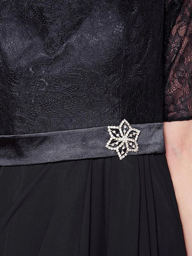 Detail of the lace sash with a sparkling crystal brooch on the mother of the bride dress.