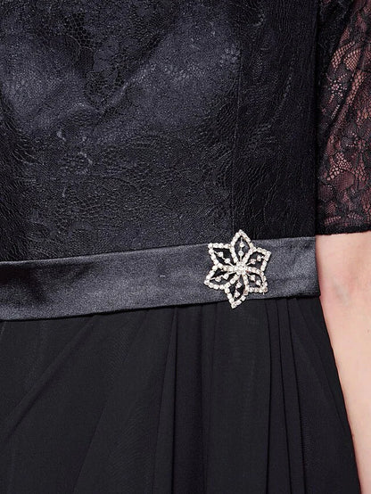 Detail of the lace sash with a sparkling crystal brooch on the mother of the bride dress.