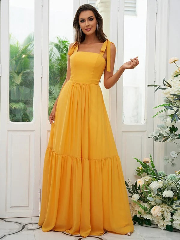 Woman wearing a light blue A-line chiffon bridesmaid dress with ruffled straps, standing outdoors.