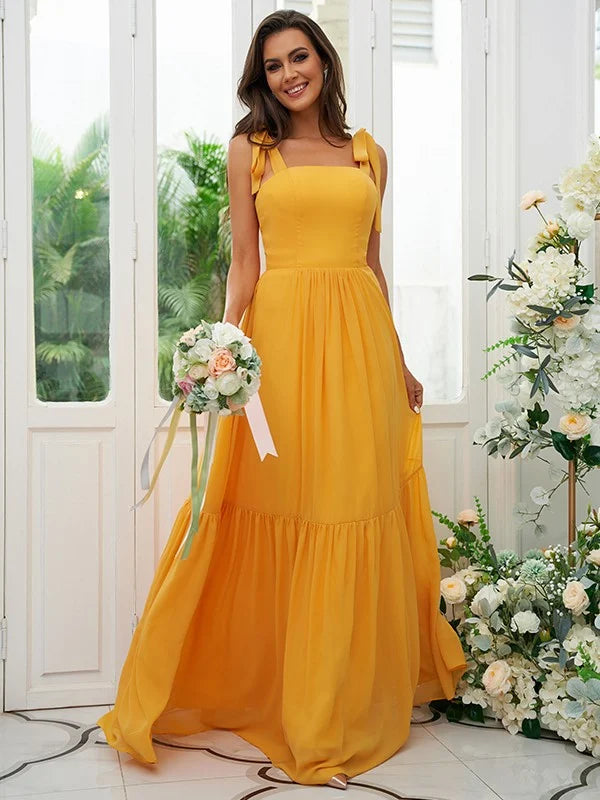 Woman posing in a light blue A-line chiffon bridesmaid dress with ruffled straps.
