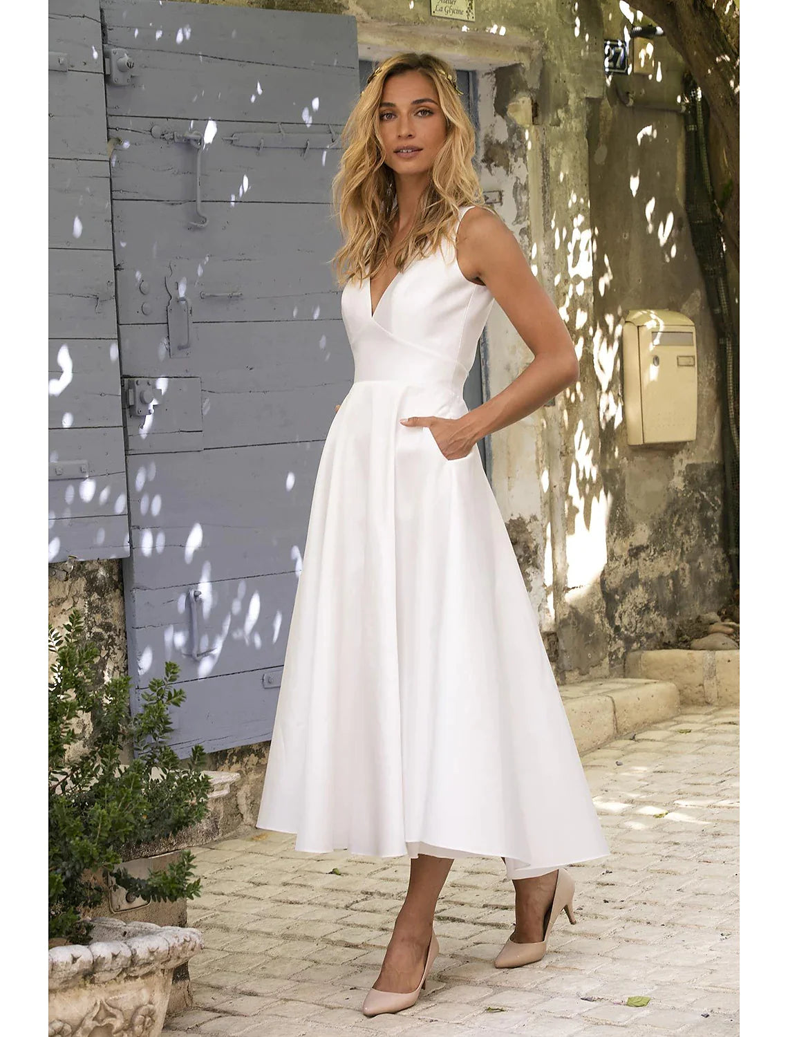 Woman wearing elegant white A-line deep V-neck maxi dress, front view.