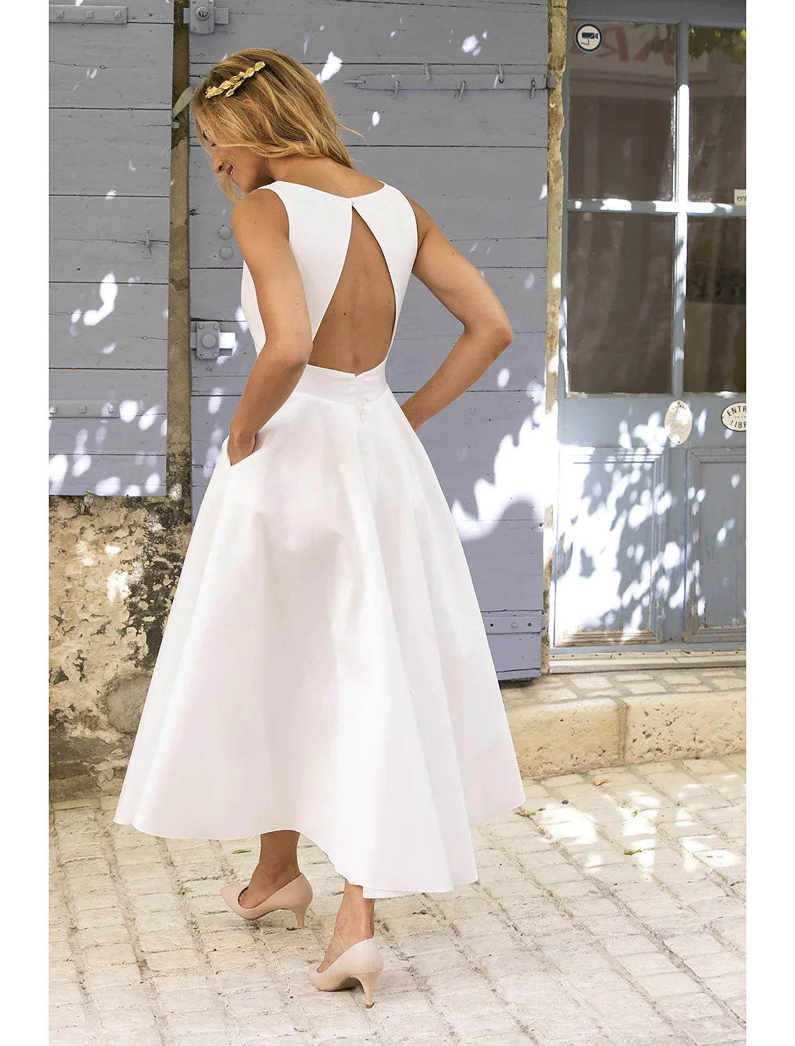 Woman in white A-line maxi dress, back view showcasing backless design.