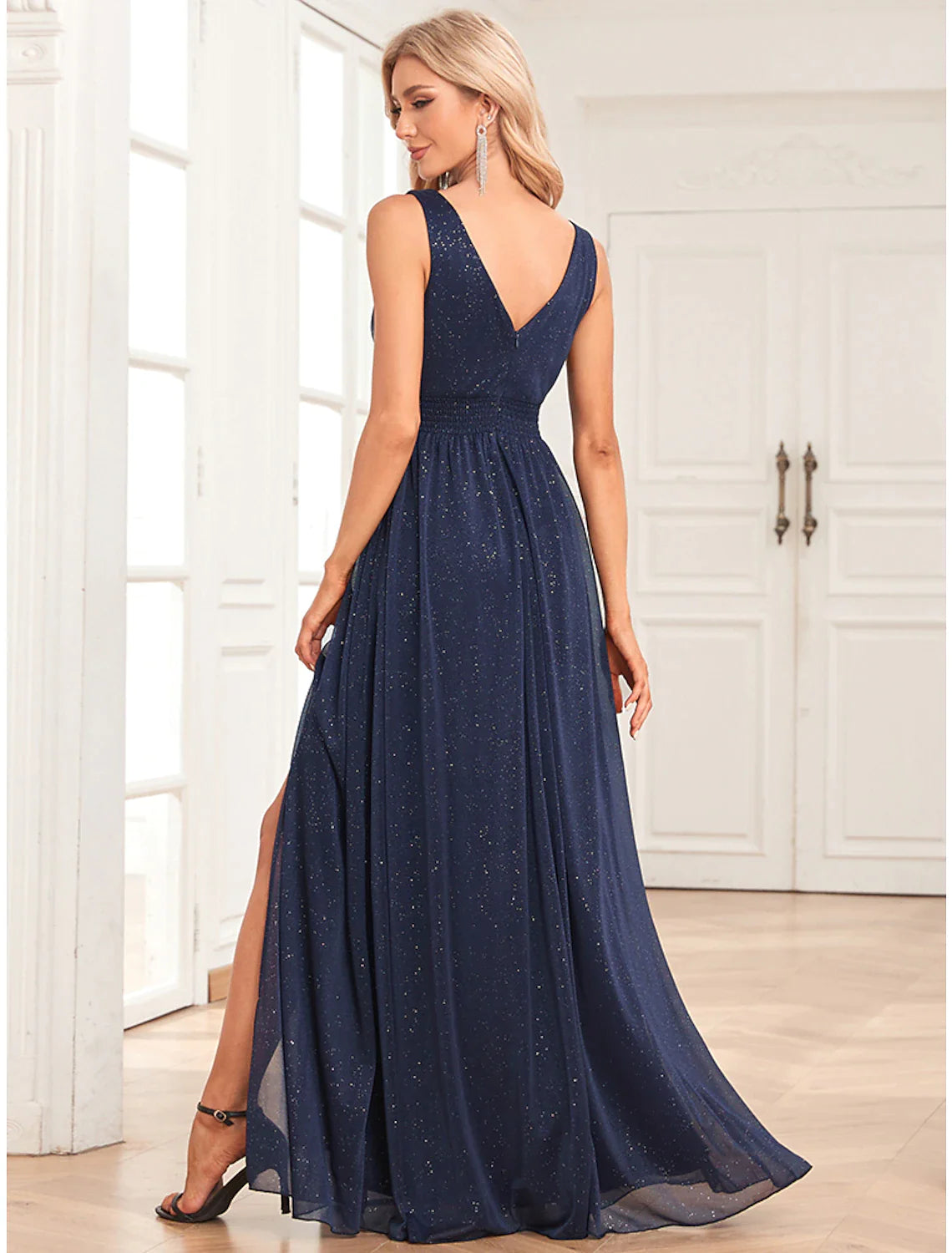Back view of a woman in a dark A-line empire evening gown with a V-back.