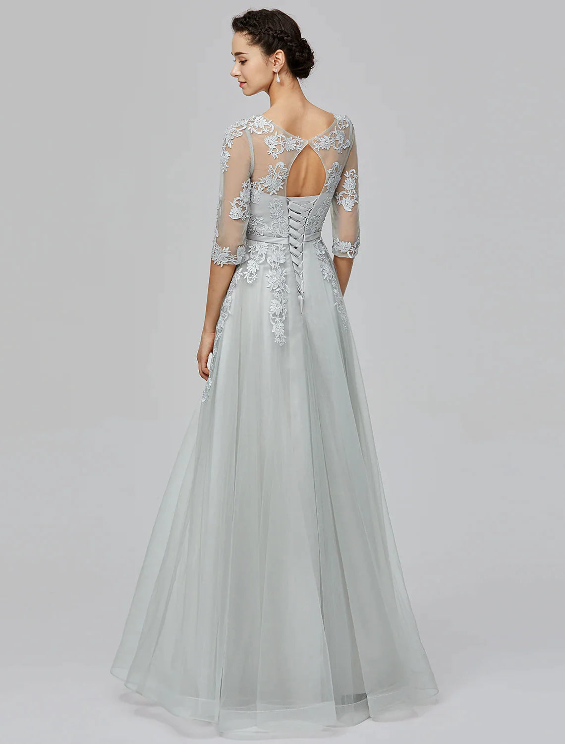 Woman in A-Line Empire tulle dress, side view, showcasing bow appliques on the skirt.