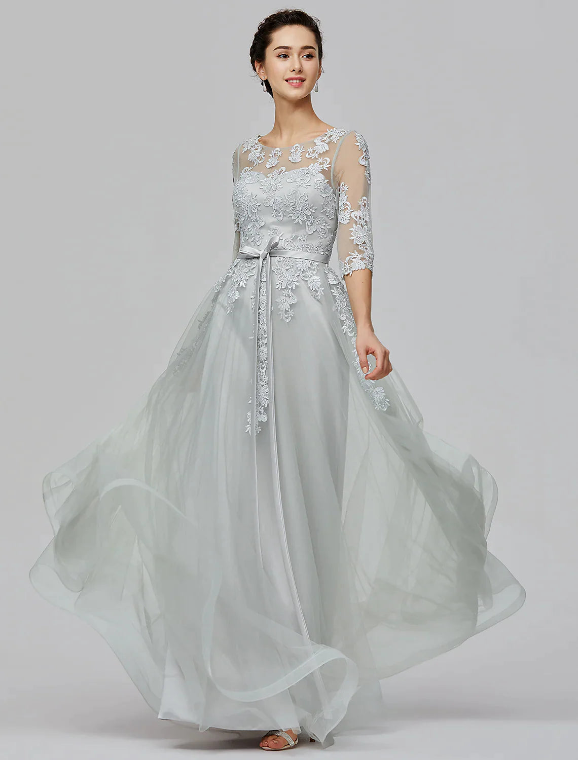 Back view of a woman wearing an A-Line Empire tulle dress, highlighting the illusion back and bow details.