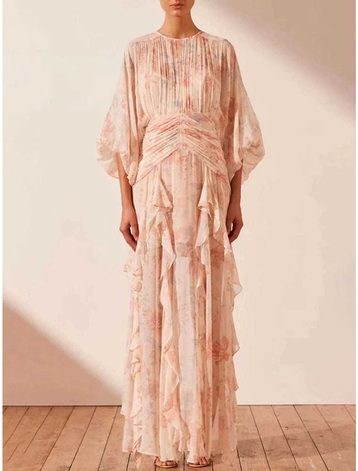 Woman wearing an elegant A-line floral maxi dress with long sleeves and ruffles.