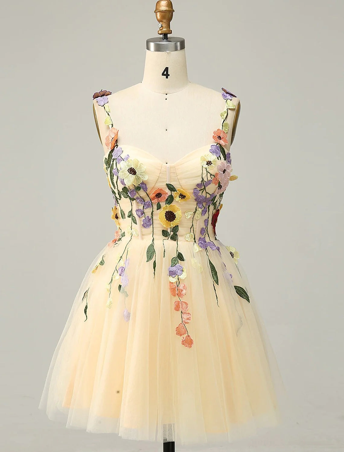 Model wearing an A-line floral tulle homecoming dress with spaghetti straps and appliques.