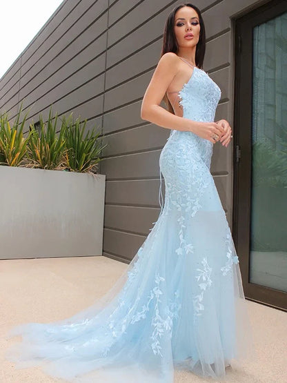 Back view of a woman in an A-line halter lace tulle long prom gown, showing the flowing skirt.