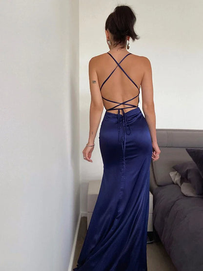 Back view of a woman in a light blue ruched halter prom dress, showing the elegant train.