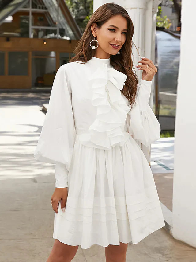 Back view of a woman in a dark A-line high neck long sleeve ruffled mini dress.