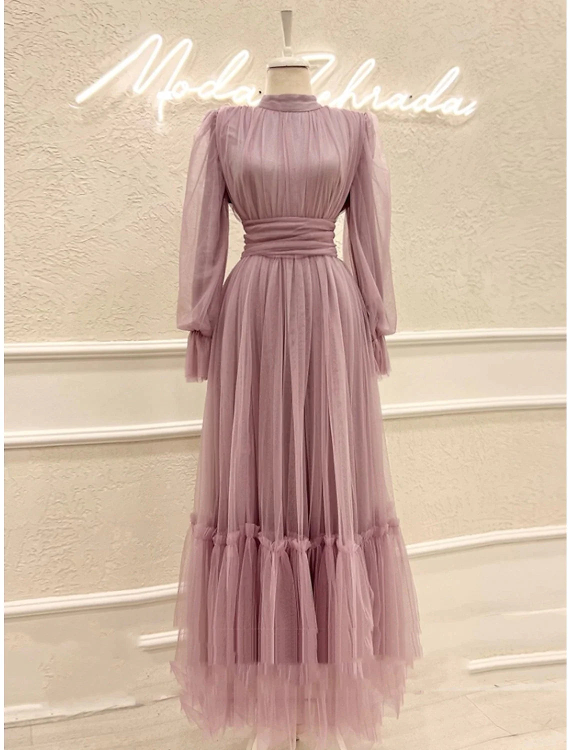 Side profile of a woman in an A-line high neck long sleeve tulle prom dress.