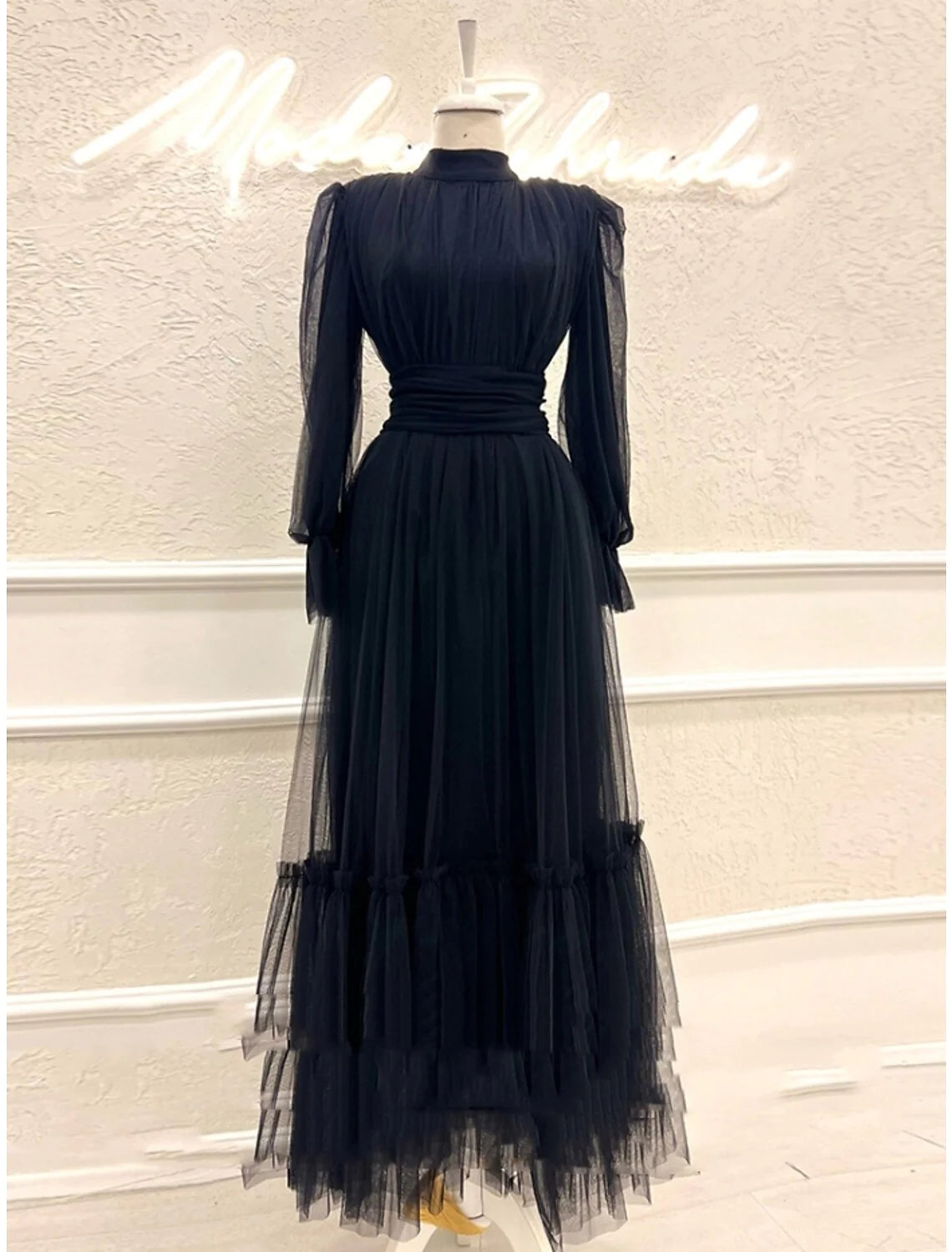 Model posing in an elegant A-line long sleeve formal dress with pleated tulle.