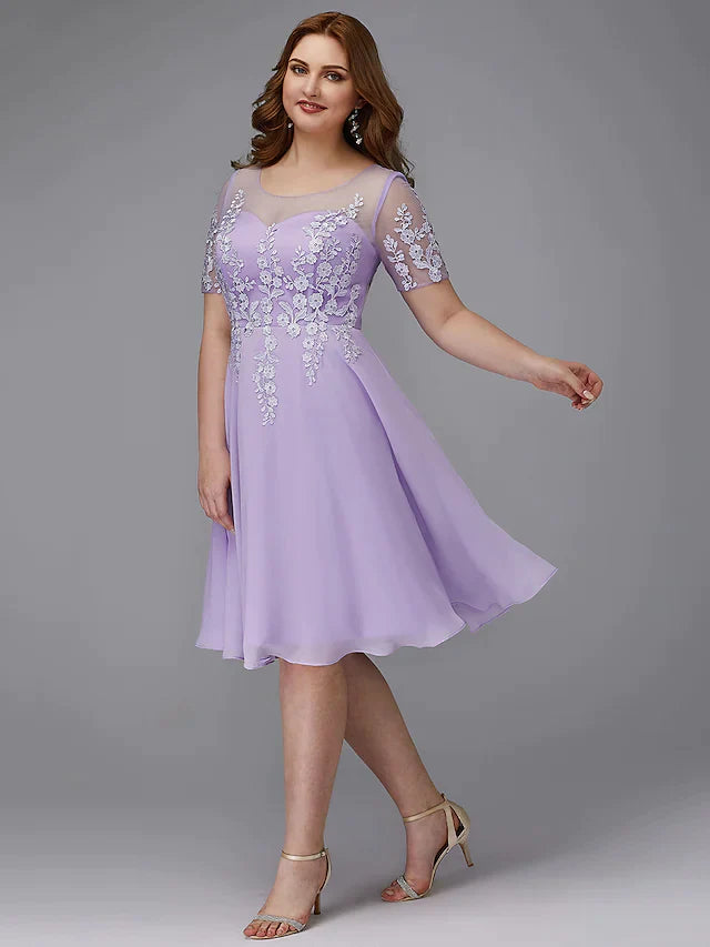 Front view of an elegant navy A-Line plus size cocktail dress with illusion neck and short sleeves.