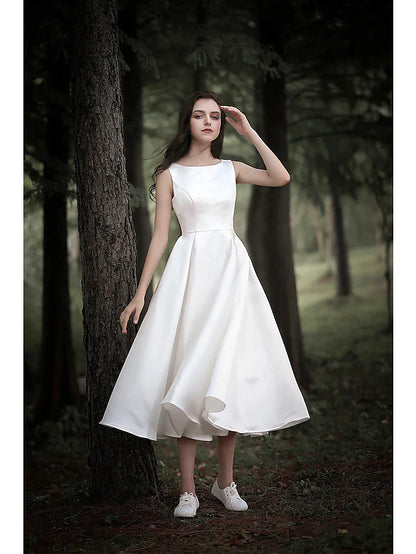 Model wearing an elegant white A-line tea length wedding dress with cap sleeves and a jewel neck, front view.