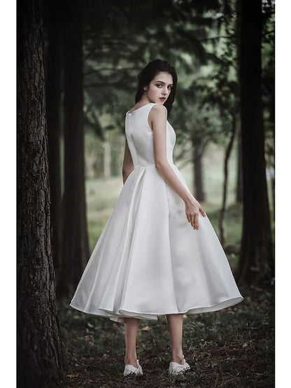 Model in a white A-line tea length wedding dress with cap sleeves, side view, showcasing the flowing skirt.