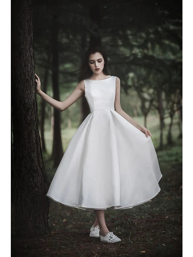 Model posing in the white A-line tea length wedding dress, back view, highlighting the dress silhouette.
