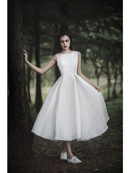 Model posing in the white A-line tea length wedding dress, back view, highlighting the dress silhouette.