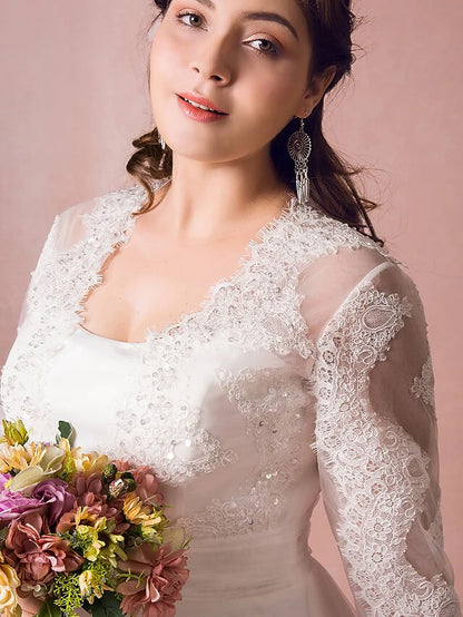 Close-up of intricate lace on the long illusion sleeve and jewel neckline.