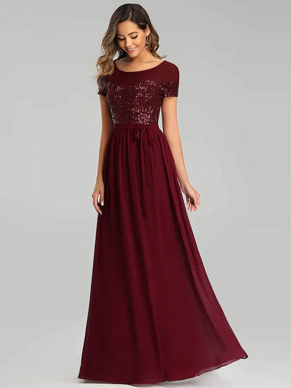 Woman wearing an elegant light blue A-line chiffon bridesmaid dress with sequin details and a sash.