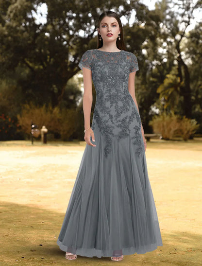 Full-length view of a woman wearing an elegant A-line jewel neck short sleeve lace pleated floor-length evening gown.