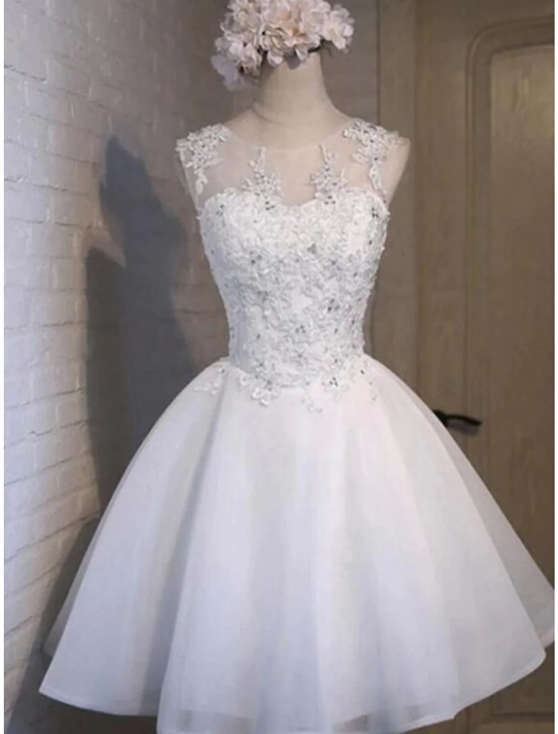 Woman wearing an elegant A-line short homecoming dress with floral appliques and a jewel neck.