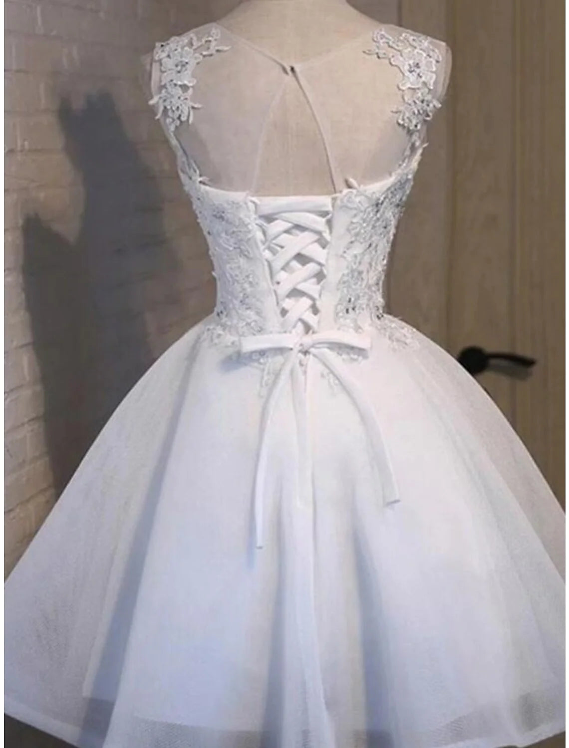 Back view of a woman in a sleeveless A-line mini dress with delicate floral appliques.