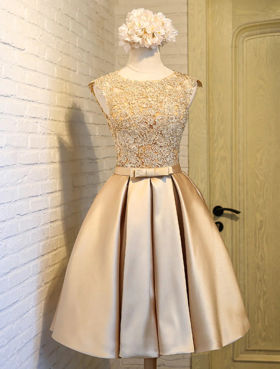 Close-up of the lace bodice and satin skirt of the knee-length dress.