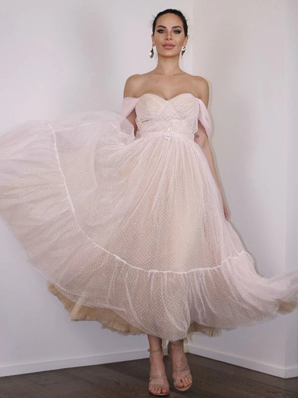 Woman wearing an A-line lace off-shoulder tea-length dress.