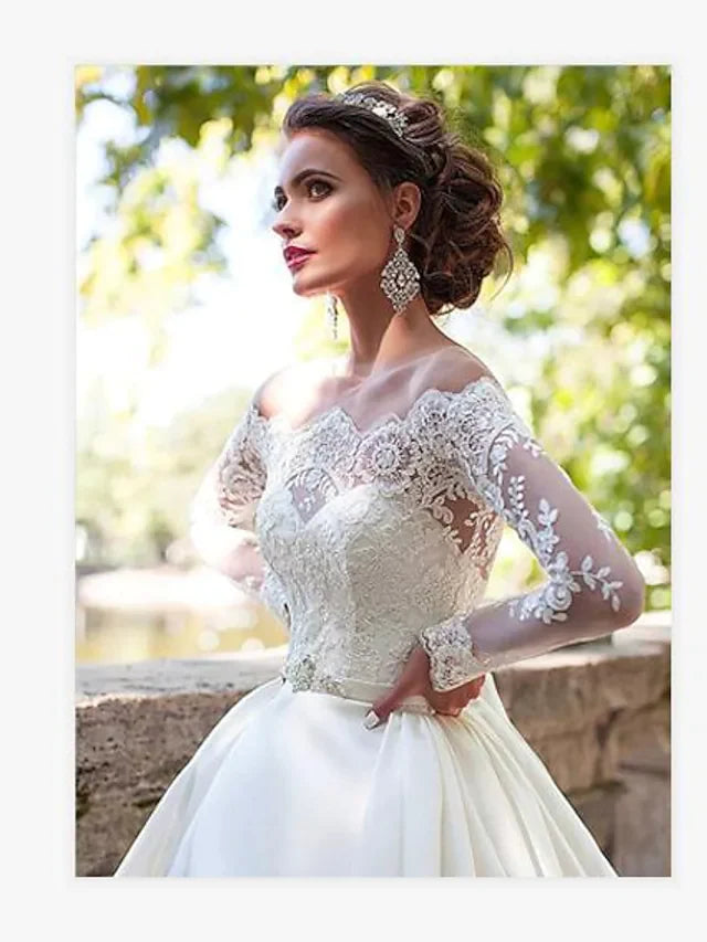 A bride in an A-line off-shoulder lace long sleeve wedding dress, viewed from the back, showing the court train.