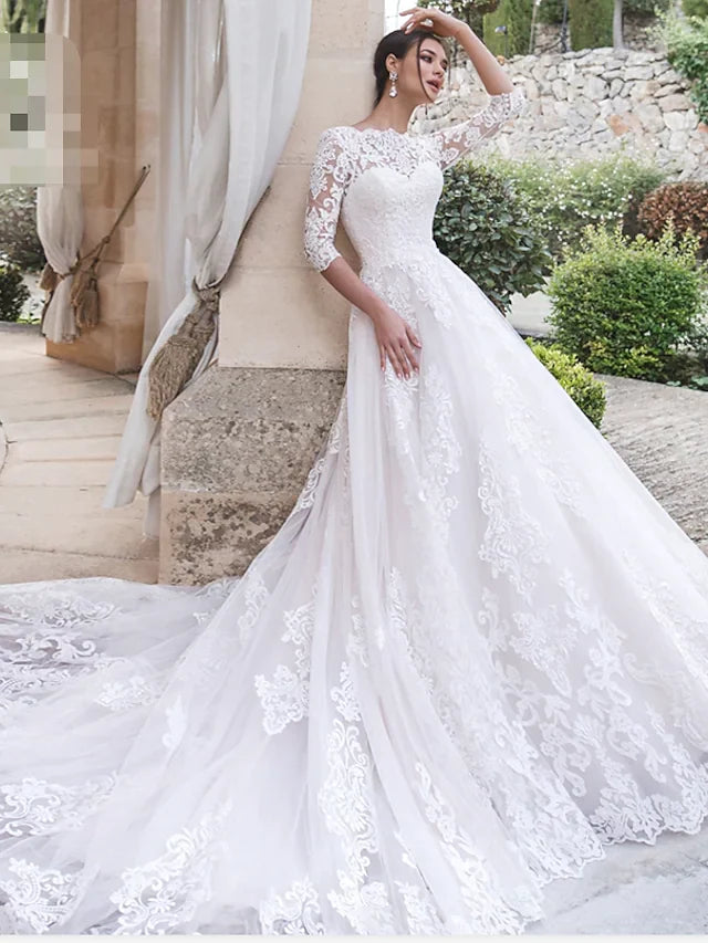 Bride in an elegant A-line off-shoulder lace wedding dress with illusion sleeves and court train.