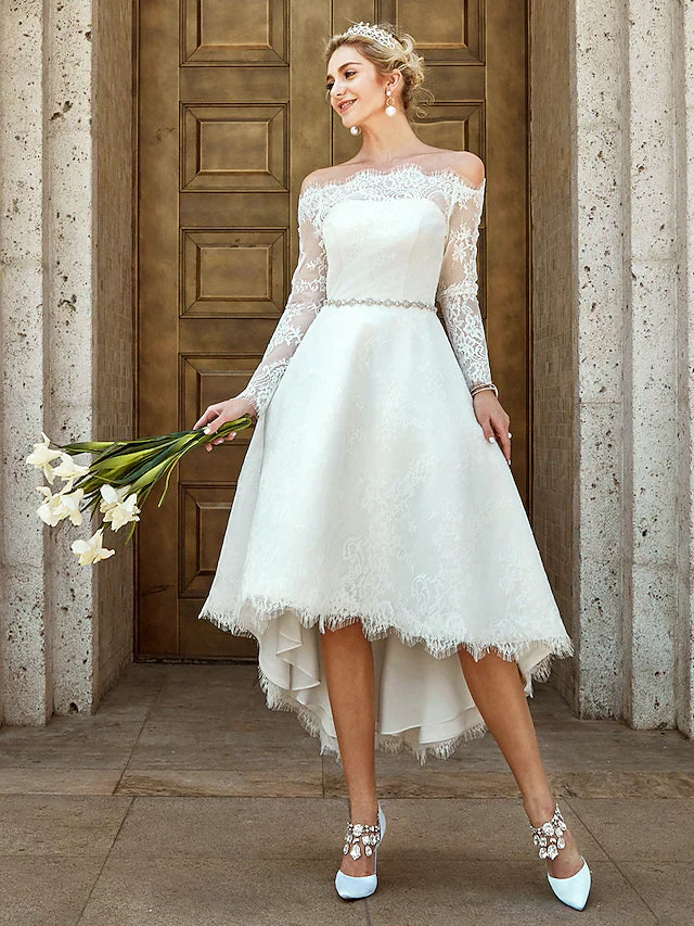 Full view of a white A-line off-shoulder wedding dress with long lace sleeves and asymmetrical lace details.