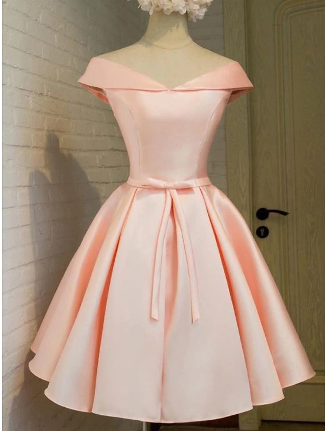 Woman wearing an elegant pink off-shoulder A-line satin short homecoming dress.
