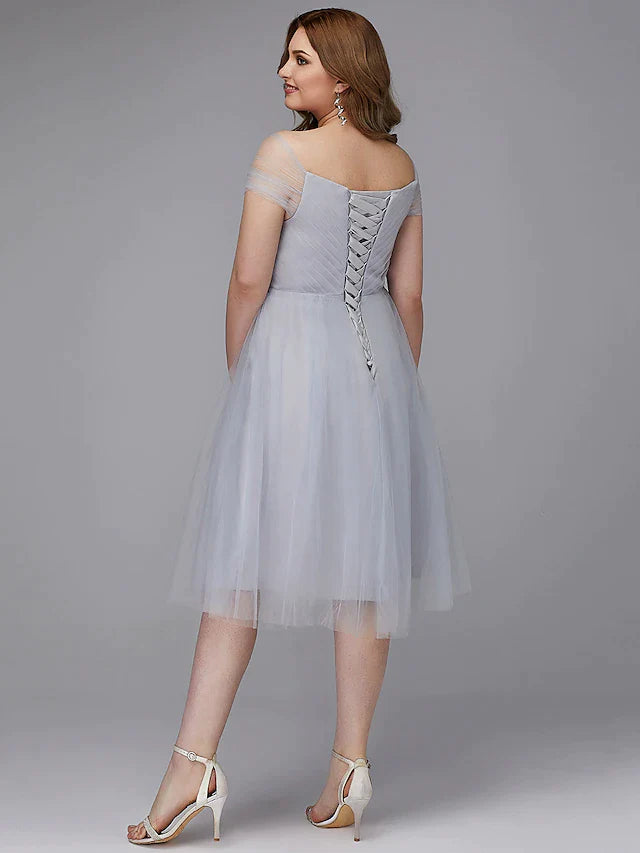 Model posing in the light-colored off-shoulder tea length dress, showing the full skirt.