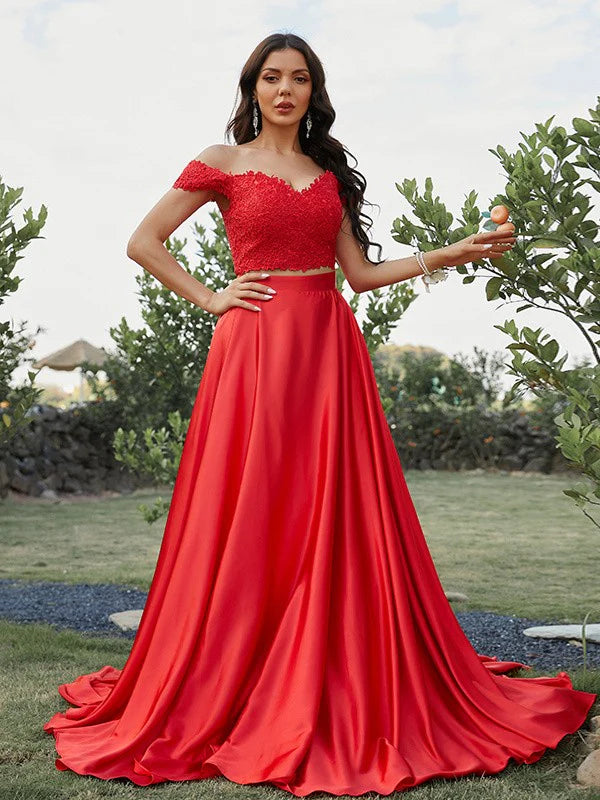Model wearing an elegant A-line off-shoulder two-piece prom dress with applique details.