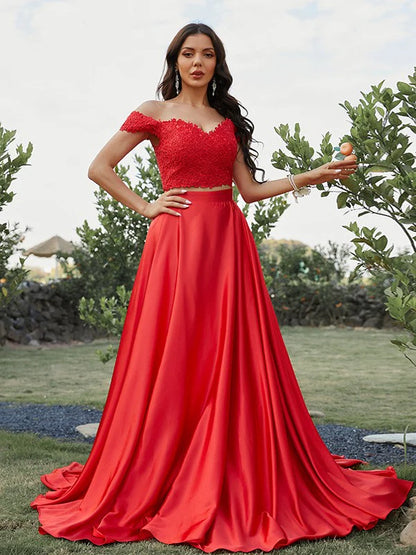 Model wearing an elegant A-line off-shoulder two-piece prom dress with applique details.