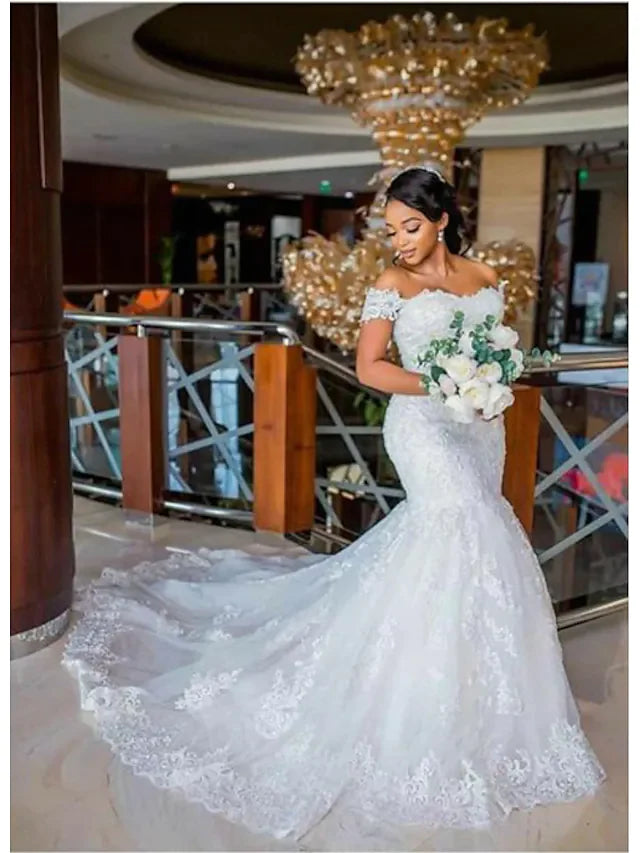 Plus size bride in elegant off-shoulder A-line wedding dress with lace appliques and chapel train.
