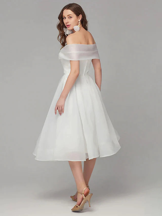 Close-up of the off-shoulder neckline and intricate criss-cross pleats on the white organza dress.